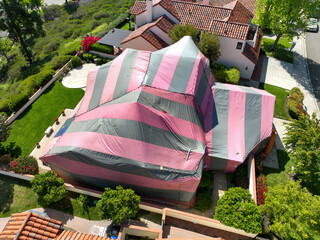 Covered villa with a red and gray tent while being fumigated for termites, San Diego, California, USA. April 17th, 2022