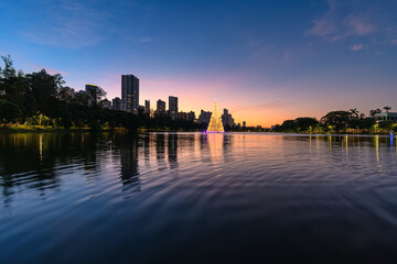 Igapo lake at sunset during christmas, Londrina - PR, Brazil. Beautiful city lake with christmas tree shining in the middle of the lake and the city buildings on background.