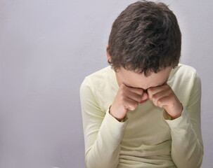 boy crying with hand over face crying alone and all by himself with white background