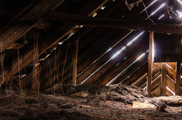 abandoned attic of an abandoned house, you can see wooden ceilings. Sunlight passes through cracks...