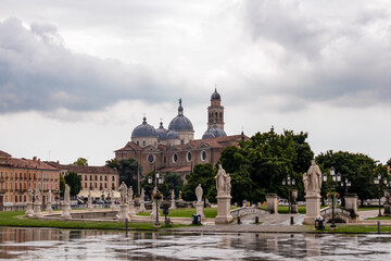 Fototapeta na wymiar Scenic view after strong rain on Prato della Valle, Abbey of Santa Giustina, square in city of Padua, Veneto, Italy, Europe. Rain storm, black clouds in sky. Isola Memmia surrounded by canal, statues