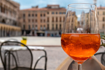 Typical italian alcoholic aperitif (aperitivo) served in a bar on  Piazza delle Erbe in Padova, Veneto, Italy, Europe. Aperol Spritz with ice cubes on a summer day. Padua, birth place of Aperol
