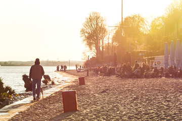 People relaxing at the beach at the Elbe River in Hamburg during colorful sunset