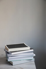 There is a stack of books on a beige table against a white wall. Scandinavian style. Minimalism. Place for text