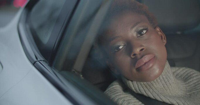Young black woman opening her eyes and smiling while traveling inside a car through the city