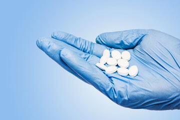 Hand in blue glove. Holding pills isolated on white. Drugs background in background. Pharmacy tablets cut out .