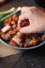Fried Pork Belly with Fish Sauce Served on a Gray plate on a black wooden floor.
