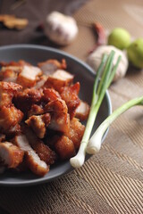 Fried Pork Belly with Fish Sauce Served on a Gray plate on a black wooden floor.