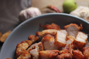 Fried Pork Belly with Fish Sauce Served on a Gray plate on a black wooden floor.