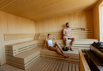 Young couple relaxing in the sauna and watching winter forest through the window