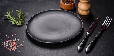 Empty round black plate on dark moody black background with copy space