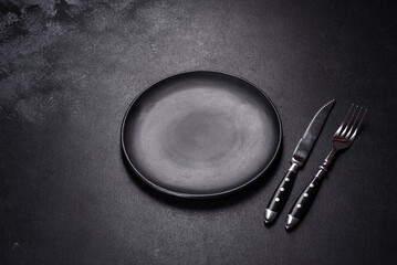 Empty round black plate on dark moody black background with copy space