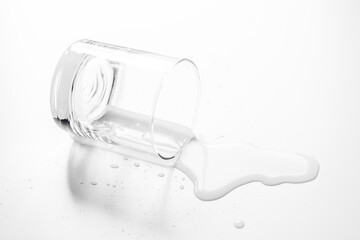 .a glass of water spilled on a white table- Image