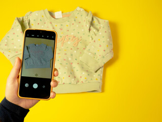 A woman photographs children's clothing for sale online. The concept of selling clothes online....