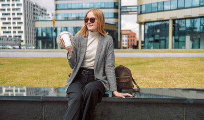 Woman holds a eco paper cup with coffee or tea and walks in spring park. Drink coffee time....
