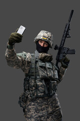 Shot of joyful serviceman from ukraine posing with mobile phone against grey background. Information war.