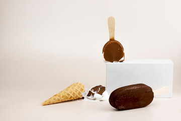 Melting chocolate popsicles on white podium, Ice cream waffle cone and chocolate ice cream with stick on light background. Refreshing summer creative concept.