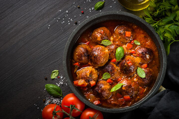 Meatballs in tomato sauce in the skillet on dark stone table. Top view copy space.