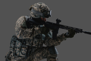 Shot of serviceman dressed in protective helmet and uniform aiming rifle.