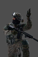 Fototapeta premium Portrait of attacking soldier equiped with modern uniform and weapon against gray background.
