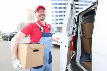 Smiling courier with parcels near delivery van