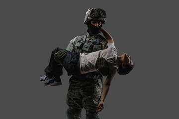 Shot of serviceman dressed in camouflage uniform rescuing little injured boy.