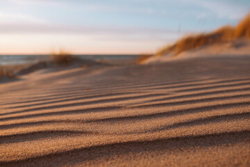 Dune waves and sand pattern. Wave, sand dunes, dry desert, brown or yellow colored. The sand changes shape due to the wind to form sand ripples and jagged lines. Selective focus