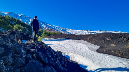 Tourist man hiking on volcanic landscape of volcano mount Etna, in Sicily, Italy, Europe. Pine and...