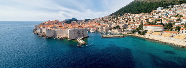 Dubrovnik stone Fortress and Harbor, sunny, deep blue sea, moving boat, tourists. Panoramic, aerial view of the historic center of Dubrovnik, Croatia.