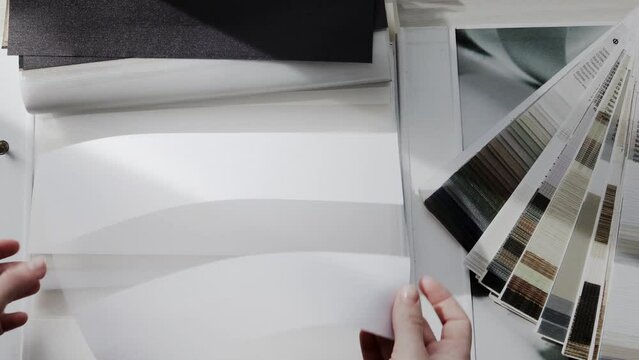 Woman fliping through catalog with roller blinds or window shade. Duo window roller system day and night. Choice of roller blinds.