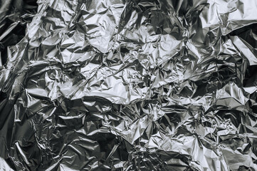 Background, texture of silver shiny foil, colored crumpled old paper for packing goods. Close-up photo, top view, copy space, abstraction.