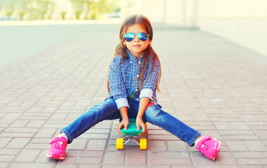 Portrait of little girl child posing with skateboard in the city