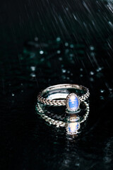 ring with Moonstone   on black background  with water drops- Image