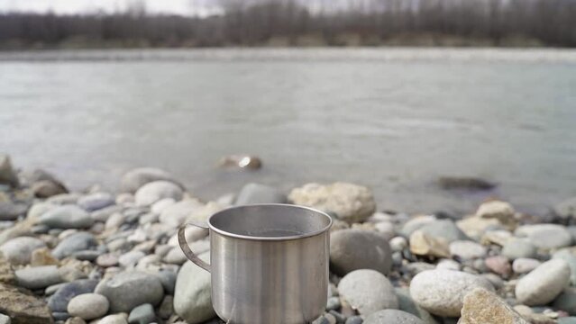 Idyllic Camping Scene. Water in a Metal Mug Boils on a Gas Burner. Hike. Breakfast on the River Bank