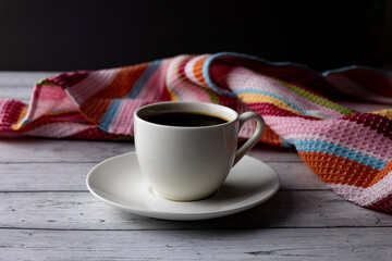A cup of coffee on a wooden table, and a colored towel, retro style