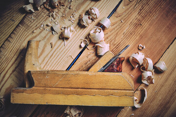 Old wooden carpenters tool plane on a wooden background.