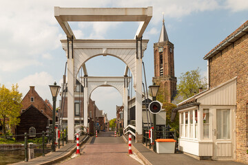 White old drawbridge over the river Vecht and in the background the church tower in the Dutch village of Loenen aan de Vecht.