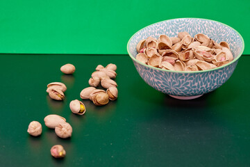 Fototapeta na wymiar Tasty organic pistachios on a green table.