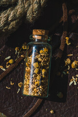 Close-up image of a glass bottle with dried chamomile