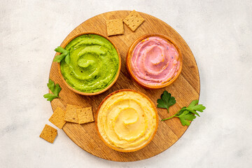 Chickpeas spinach and beets hummus in bowls, top view, flat lay