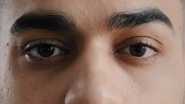 Extreme facial close up young hispanic male eyes arab man with brown eyeballs blinking looking at camera demonstrate perfect eyesight after ophthalmology procedure feeling wellness helth care concept