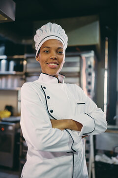 Professional Black Chef Standing With Her Arms Crossed And Looking At Camera.