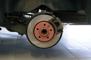 A new brake disc is installed on the car. The brake caliper is corroded. Selected focus.
