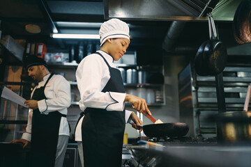 Below view of black female chef preparing food in the kitchen.