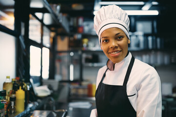 African American female chef working at restaurant and looking at camera.