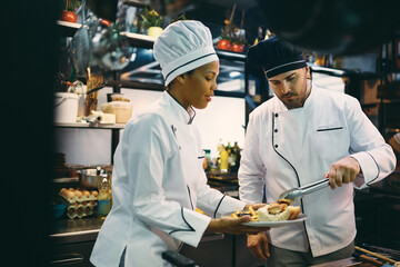 Multiracial chefs preparing food in kitchen at restaurant.