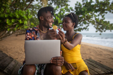 two african cryptocurrency investors on the beach hold a Bitcoin and Ethereum coin and use a...