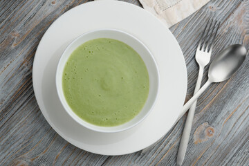 Broccoli puree on a wooden table, side view. Green soup in a white cup. Vegetarian puree soup....