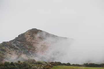 Big mountain in the fog. Low clouds stop at the mountain