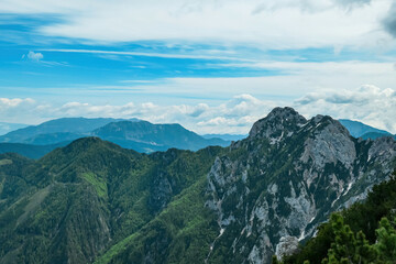 Panoramic view from the summit of Goli Vrh on rocky sharp mountains of Kamnik Savinja Alps in Carinthia, border Austria and Slovenia. Green spring meadow in Vellacher Kotschna. Mountaineering. Freedom